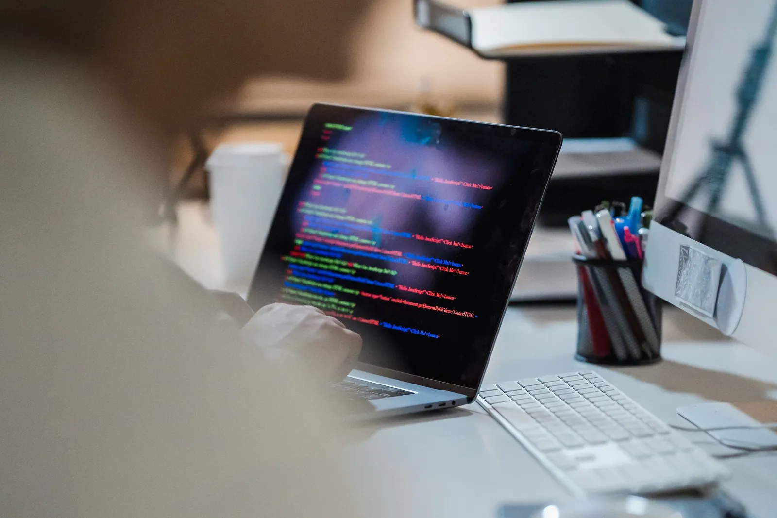 Laptop on an office desk showing colorful code in an editor